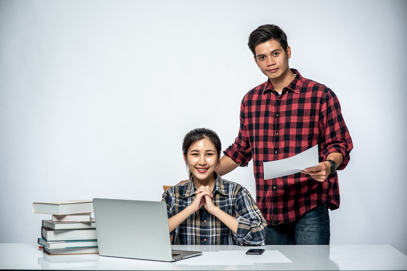 Men teach women how to work with laptops at work.